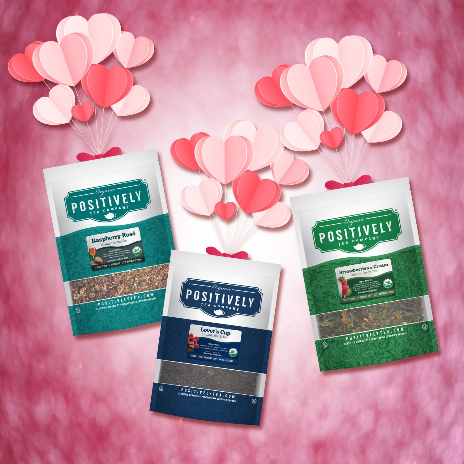 Three packages of 'Positively' tea on a pink background with heart-shaped balloons.