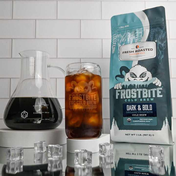 Fresh Roasted Coffee Dark & Bold Frostbite Cold Brew, 2lb bag next to a glass of iced cold brew, rich medium roast with nutty chocolate undertones.